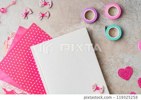Creative supplies for scrapbooking and crafting on a textured surface with decorative tape and heart confetti 119325258