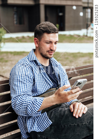 Young man sitting on a bench in a park 119325283