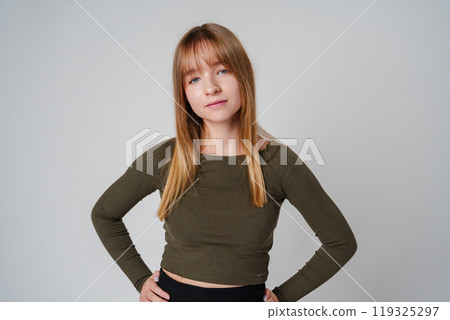 A young woman with straight hair wearing a green top poses against a neutral background 119325297