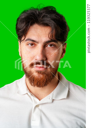 A man with a serious expression stands against a vibrant green background 119325377