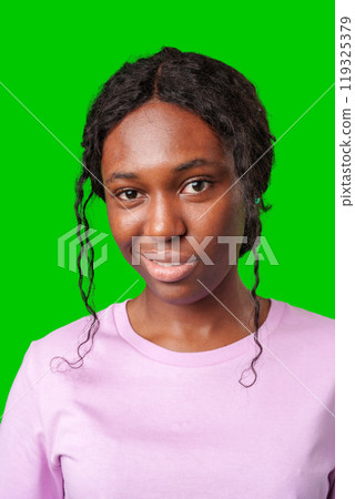 Young woman with curly hair shows a skeptical expression against a bright green background Young woman with curly hair shows a skeptical expression against a bright green background 119325379