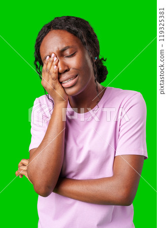 Woman expressing frustration while standing against a bright green background 119325381