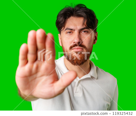 Man with a beard holding up his hand and looking at the camera against a bright green background Man with a beard holding up his hand and looking at the camera against a bright green background 119325432