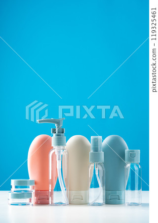 Variety of travel-sized containers displayed against a bright blue background 119325461