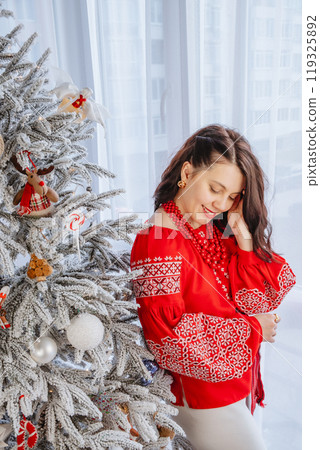beautiful woman in ukrainian traditional clothes decorating christmas tree 119325892
