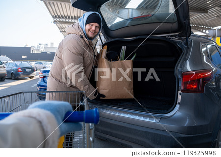 Man Loading Groceries into Car Trunk Man Loading Groceries into Car Trunk 119325998