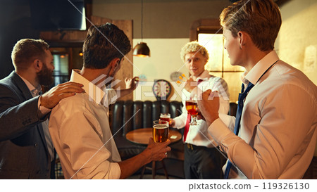 Friday mood. Men cheer as one successfully throws dart, enjoying their drinks and celebrating together. Friday mood. Men cheer as one successfully throws dart, enjoying their drinks and celebrating together. 119326130