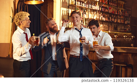 Group of colleagues playfully cheer as they playing games in bar, enjoying fun moment during their outing. Group of colleagues playfully cheer as they playing games in bar, enjoying fun moment during their outing. 119326138