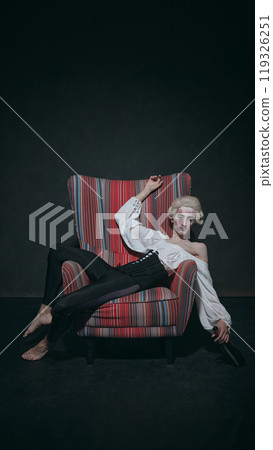 Young man with pale face with lipstick marks on face, leans back with bottle, creating amusing vibe of party aftermath in baroque setting. Young man with pale face with lipstick marks on face, leans back with bottle, creating amusing vibe of party aftermath in baroque setting. 119326251