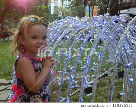 A little girl is standing in front of a sculpture that has lights on it. A little girl is standing in front of a sculpture that has lights on it. 119326535