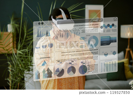 High angle shot of mature African American woman testing VR goggles to work remotely with business statistics 119327850