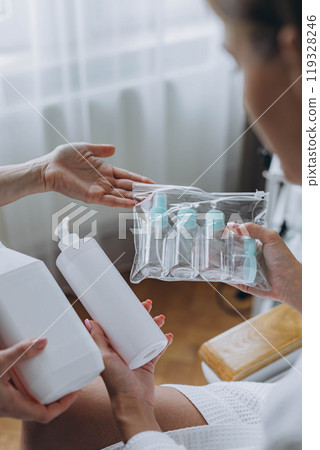 Cosmetologist shows the client a cosmetic product and travel plastic bottles,cream bottle mockup. 119328246