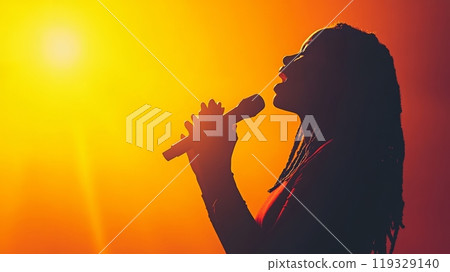 Silhouette of a singer holding a microphone against a vibrant sunset background. 119329140