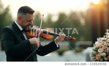 Man playing violin outdoors during sunset, elegant attire, flower arrangement nearby. Man playing violin outdoors during sunset, elegant attire, flower arrangement nearby. 119329356