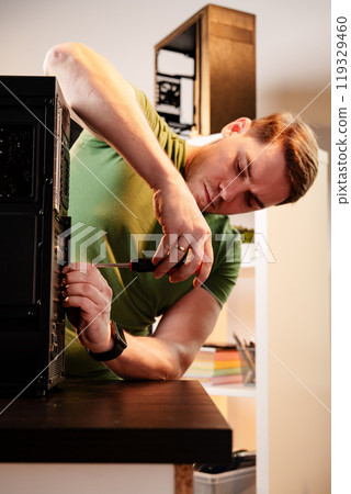 Man assembles a computer system unit at home Man assembles a computer system unit at home 119329460