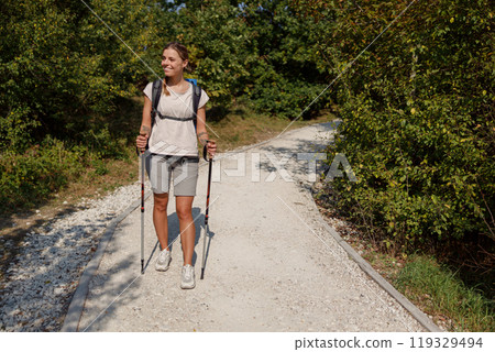 A Hiker Truly Enjoying the Beautiful Nature While Trekking on a Scenic Trail with Walking Poles 119329494