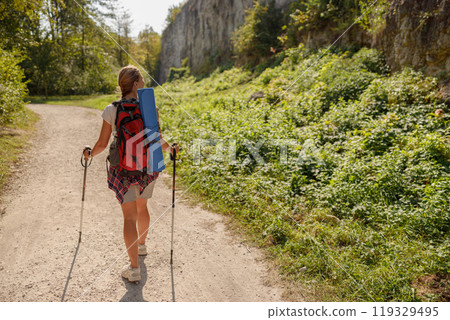 A hiker enjoying the stunning beauty of nature on a scenic trail beneath a clear sky 119329495