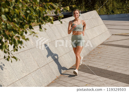 An Active and Energetic Young Woman Enjoys Jogging in a Vibrant Urban Park Setting 119329503