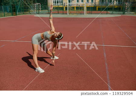 Engaging in Dynamic Stretching on a Tennis Court During a Warm Summer Day Outdoors Engaging in Dynamic Stretching on a Tennis Court During a Warm Summer Day Outdoors 119329504