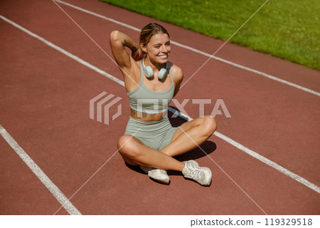 An Active Woman Happily Enjoying Her Fitness Routine on the Running Track Outdoors An Active Woman Happily Enjoying Her Fitness Routine on the Running Track Outdoors 119329518