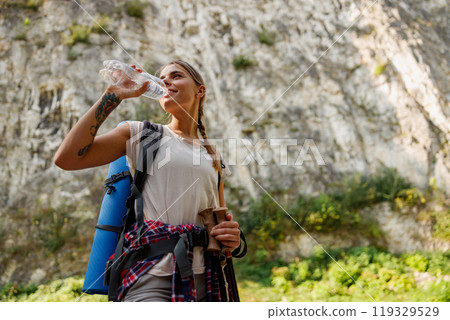 A Hiker is Enjoying a Refreshing Water Break while Surrounded by the Beautiful Nature A Hiker is Enjoying a Refreshing Water Break while Surrounded by the Beautiful Nature 119329529