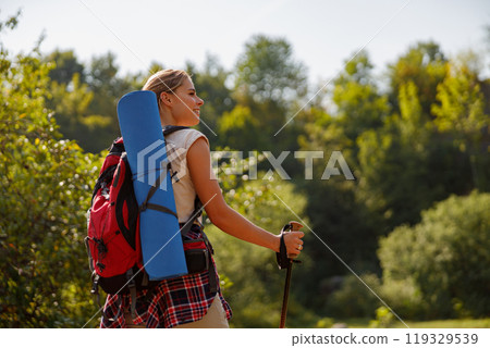A Hiker equipped with a Backpack and Camping Gear Trekking on a Beautiful Scenic Trail 119329539