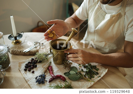 Close-up of man adds dried rose petals to a mortar and pestle. Homemade healthy and nutrition supplements Close-up of man adds dried rose petals to a mortar and pestle. Homemade healthy and nutrition supplements 119329648
