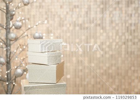 New Year interior decor made of golden boxes, Christmas tree with golden balls against golden wall. 119329853