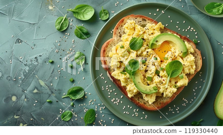 Delicious breakfast toast topped with avocado, scrambled eggs, and spinach on a green plate 119330440