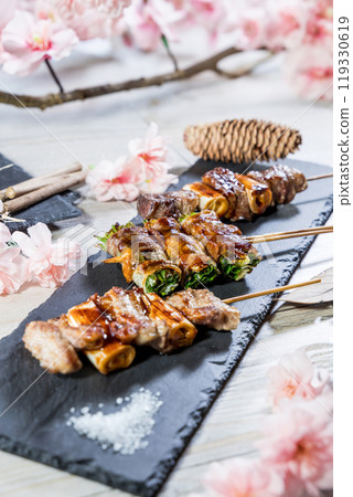 Japanese cuisine grilled beef and veg roll skewers with sakura flowers 119330619