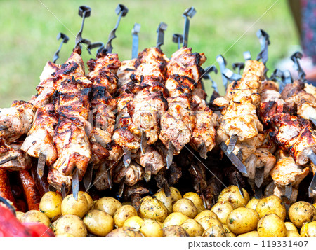 Cooking appetizing hot shish kebab or shashlik on metal skewers 119331407