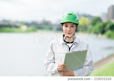 A woman in work clothes and a helmet conducting a river survey 119331520
