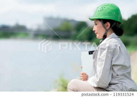 A woman in work clothes and a helmet conducting a river survey 119331524