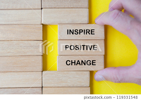 Hand pulling out wooden blocks with Inspire Positive Change text Hand pulling out wooden blocks with Inspire Positive Change text 119331548