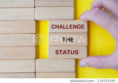 Hand pulling out wooden blocks with Challenge the Status text on yellow background. Hand pulling out wooden blocks with Challenge the Status text on yellow background. 119331549