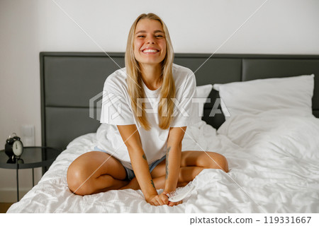 A Joyful Young Woman is Smiling Happily in Her Beautiful, Modern and Stylish Bedroom Space 119331667