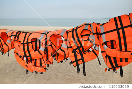 lots of orange life jackets on the background of sand, sea and straw umbrellas. High quality 4k footage lots of orange life jackets on the background of sand, sea and straw umbrellas. High quality 4k footage 119333039
