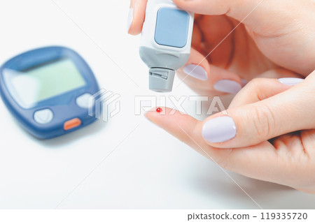 Woman is holding a glucometer Woman is holding a glucometer 119335720