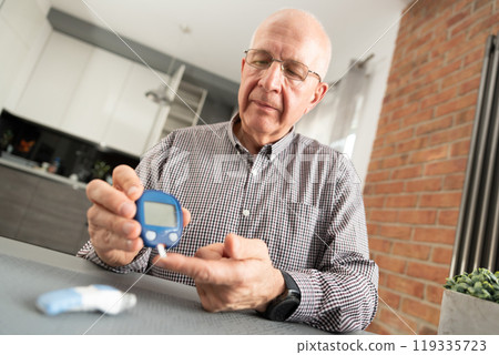 Man is taking his blood sugar reading 119335723