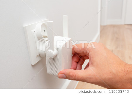 Wireless Wi-Fi repeater on white wall indoors Wireless Wi-Fi repeater on white wall indoors 119335743