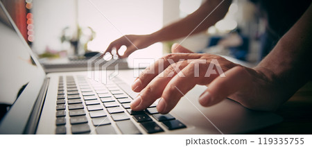 Man using laptop at home, typing hands 119335755