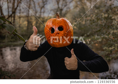 Positive man with pumpkin head for Halloween showing thumbs up, like gesture. Jack-o-lantern costume.Trick or treat. 119336556