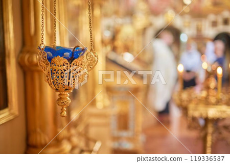 An Ornate Gold Cross Encircled by Colorful Candles Within a Beautiful Church Interior 119336587