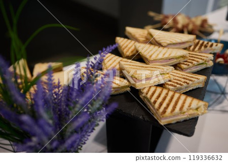 Indulge in Delicious Grilled Sandwiches Served on an Elegant Black Tray for Everyone Indulge in Delicious Grilled Sandwiches Served on an Elegant Black Tray for Everyone 119336632