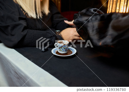 An Elegant Porcelain Teacup is Gracefully Held Against a Beautifully Dim Lighting Background 119336780