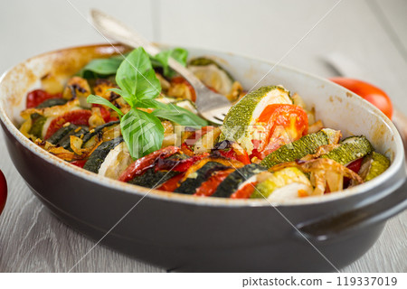 prepared baked zucchini and tomatoes in circles in a ceramic form, vegetable snack 119337019