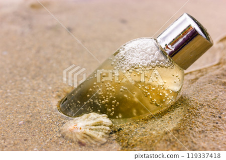 Shower product. Plastic, glass cosmetic bottle with liquid on a sandy coast, beach, shore of a sea, ocean. Natural eco cosmetics for a face body skin care. Container of shower gel shampoo, liquid soap Shower product. Plastic, glass cosmetic bottle with liquid on a sandy coast, beach, shore of a sea, ocean. Natural eco cosmetics for a face body skin care. Container of shower gel shampoo, liquid soap 119337418