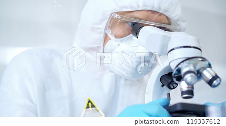 Professional scientist in protective gear is using microscope in a laboratory setting, close-up. Science and medicine concepts Professional scientist in protective gear is using microscope in a laboratory setting, close-up. Science and medicine concepts 119337612