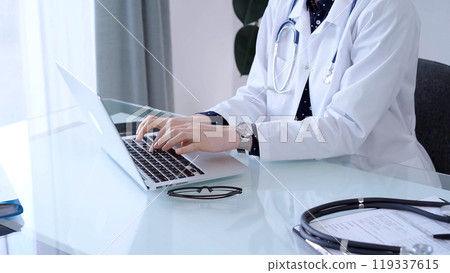 Doctor woman is sitting and typing on laptop computer, hands close up. Medicine and healthcare concept 119337615