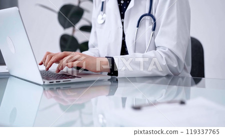 Doctor woman is typing on laptop computer at glass table in clinic, horizontal view. Medicine and pharmacy concept Doctor woman is typing on laptop computer at glass table in clinic, horizontal view. Medicine and pharmacy concept 119337765